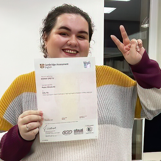 Woman wearing a striped sweater holding up a CELTA certificate
